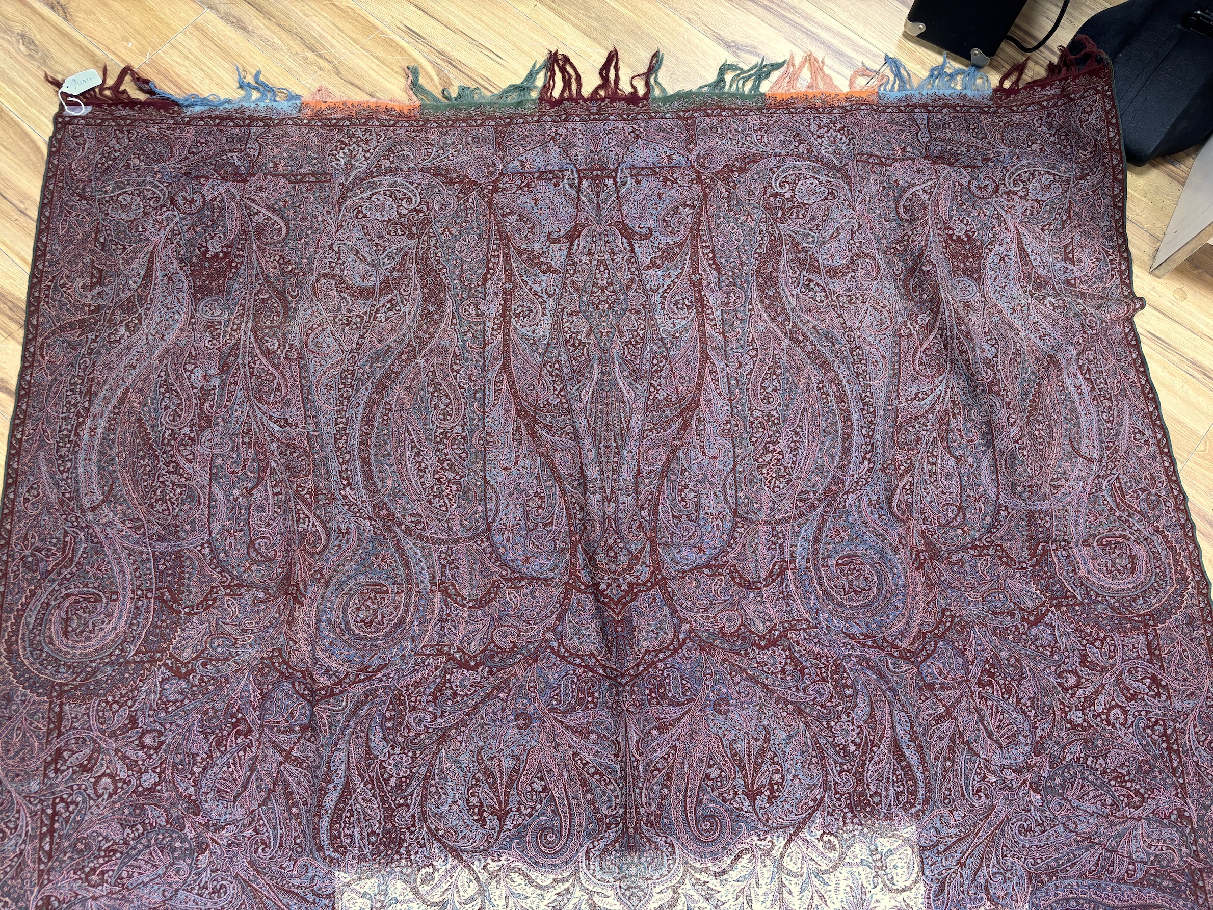 A late 19th century wool woven Paisley shawl with cream central cartouche (some damage)